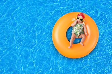 Image of Cute little baby with inflatable ring in swimming pool, top view. Space for text