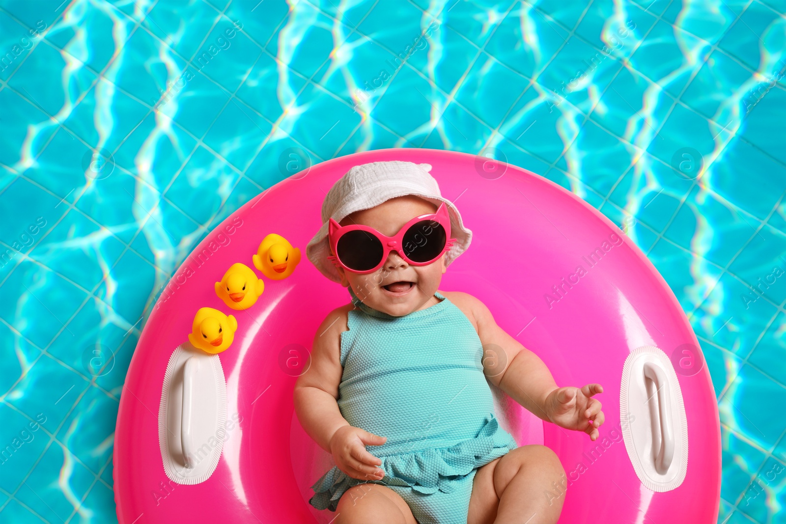 Image of Cute little baby with inflatable ring in swimming pool, top view