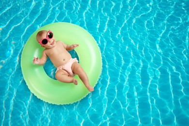 Image of Cute little baby with inflatable ring in swimming pool, top view. Space for text