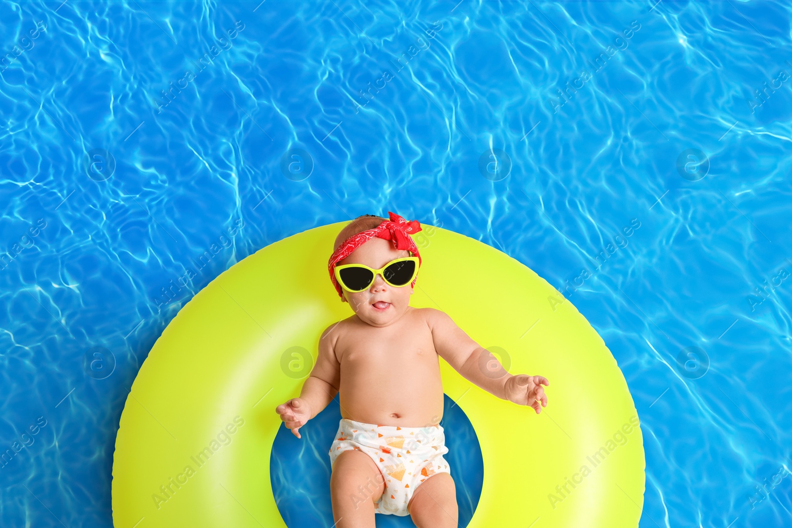 Image of Cute little baby with inflatable ring in swimming pool, top view