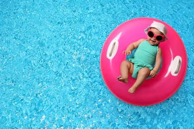 Image of Cute little baby with inflatable ring in swimming pool, top view. Space for text