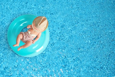 Image of Cute little baby with inflatable ring in swimming pool, top view