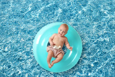 Image of Cute little baby with inflatable ring in swimming pool, top view