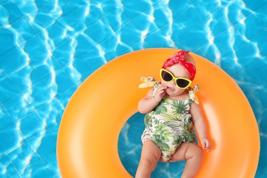 Image of Cute little baby with inflatable ring in swimming pool, top view