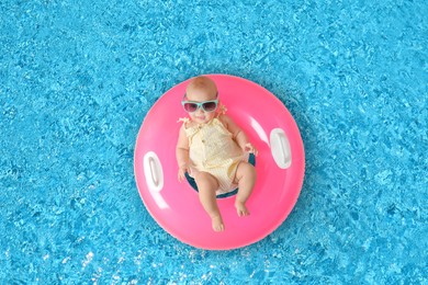 Image of Cute little baby with inflatable ring in swimming pool, top view