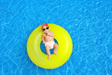 Image of Cute little baby with inflatable ring in swimming pool, top view