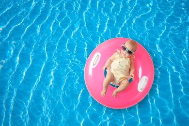 Image of Cute little baby with inflatable ring in swimming pool, top view. Space for text