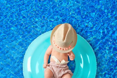 Image of Cute little baby with inflatable ring in swimming pool, top view