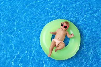 Image of Cute little baby with inflatable ring in swimming pool, top view. Space for text