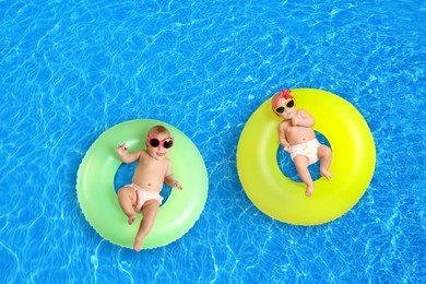 Image of Cute little babies with inflatable rings in swimming pool, top view