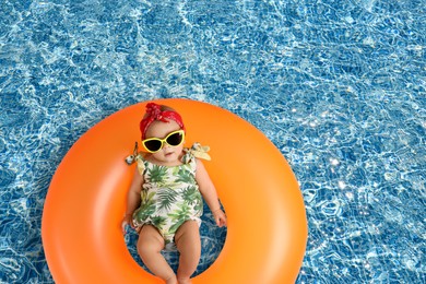 Image of Cute little baby with inflatable ring in swimming pool, top view