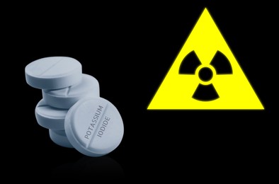 Image of Potassium iodide pills and warning sign on black background. Iodine consumption during radioactive contamination