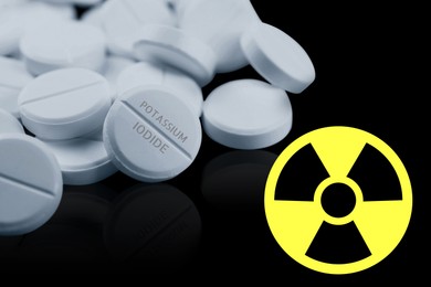 Image of Potassium iodide pills and warning sign on black background. Iodine consumption during radioactive contamination
