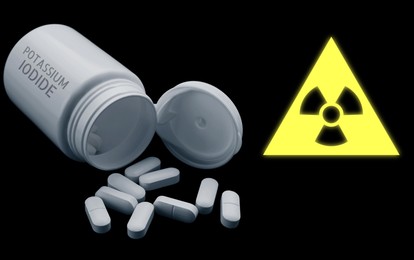 Image of Potassium iodide pills and warning sign on black background. Iodine consumption during radioactive contamination