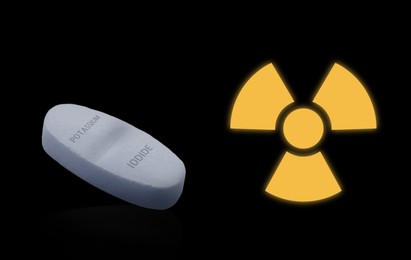 Image of Potassium iodide pill and warning sign on black background. Iodine consumption during radioactive contamination