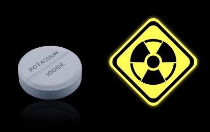 Image of Potassium iodide pill and warning sign on black background. Iodine consumption during radioactive contamination