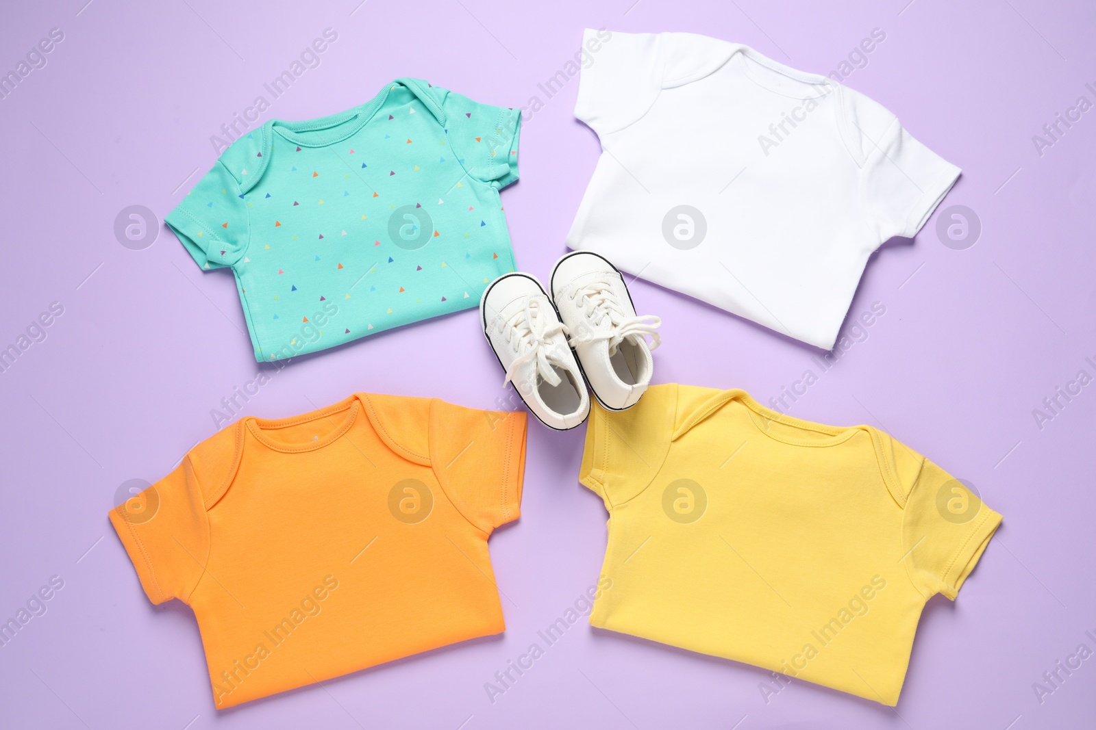 Stylish baby clothes and shoes on violet background, flat lay Photo of Stylish baby clothes and shoes on violet background, flat lay