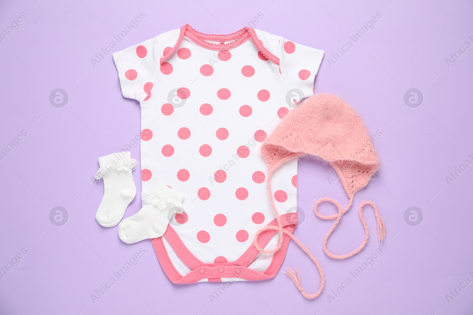 Stylish baby onesie and accessories on violet background, flat lay Photo of Stylish baby onesie and accessories on violet background, flat lay