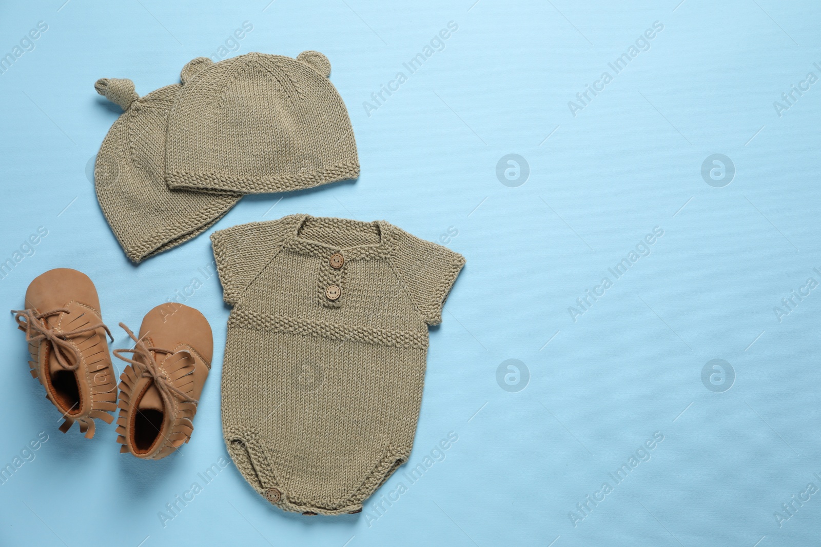 Photo of Stylish baby clothes and accessories on light blue background, flat lay. Space for text