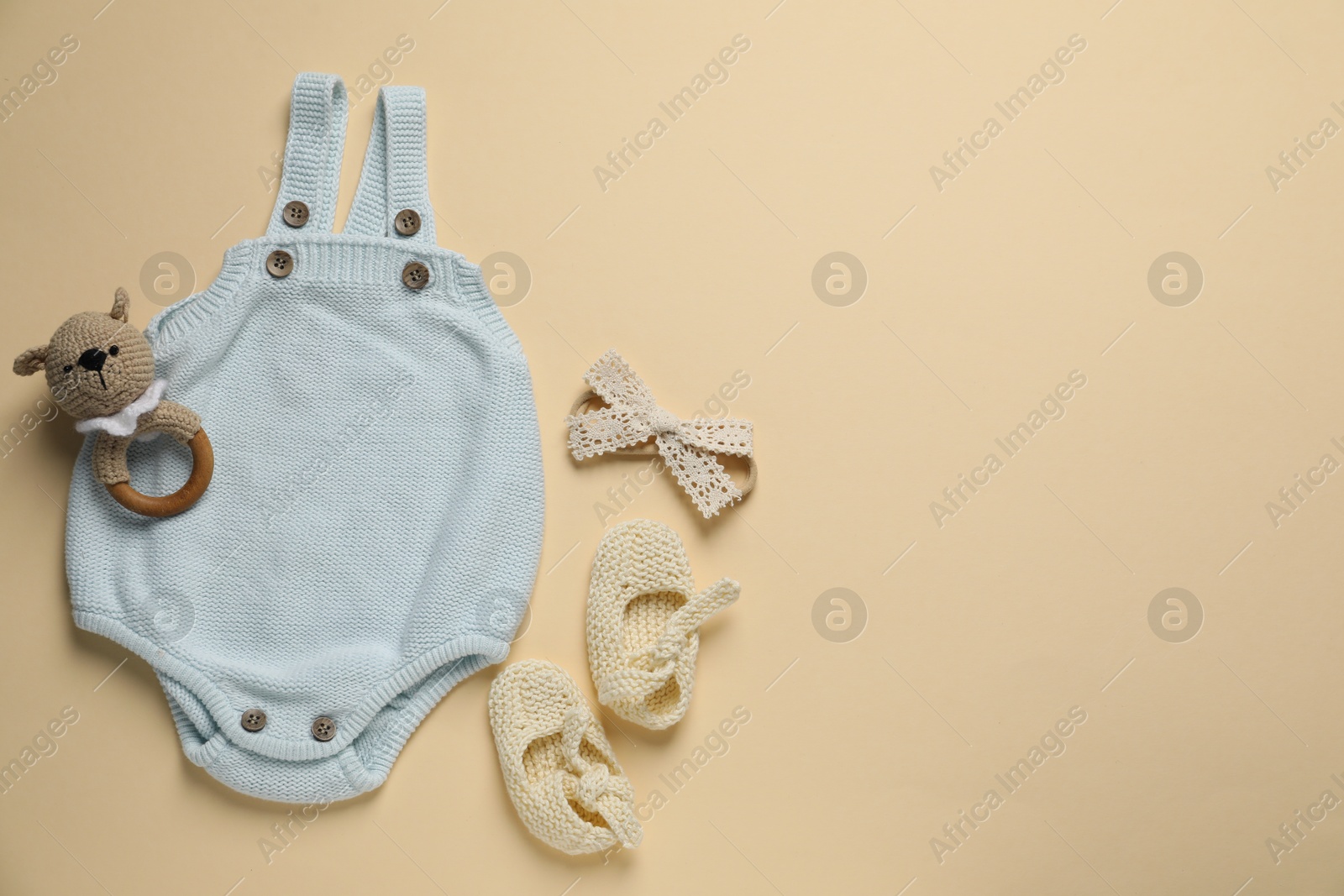 Stylish baby onesie and accessories on beige background, flat lay. Space for text Photo of Stylish baby onesie and accessories on beige background, flat lay. Space for text