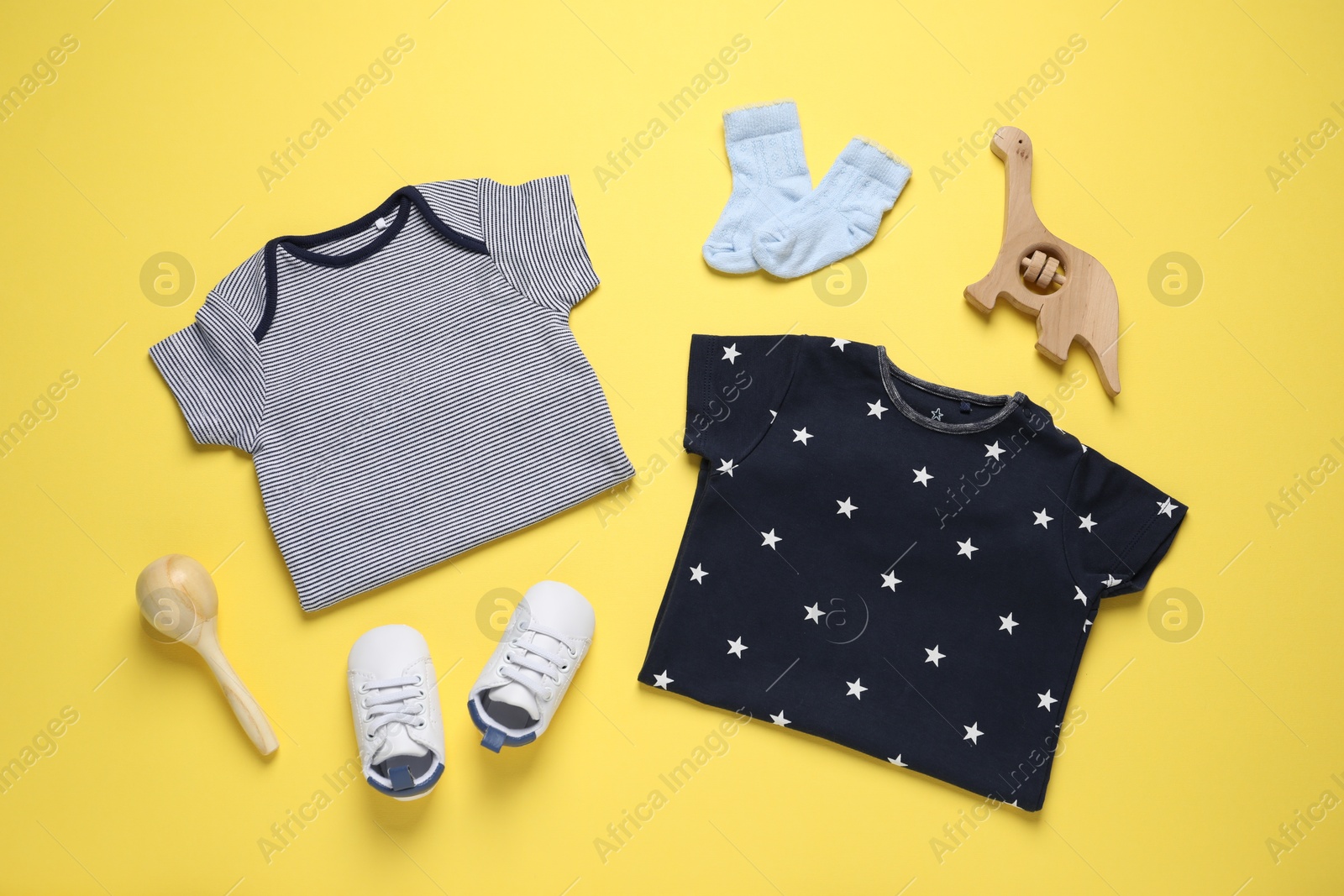 Stylish baby clothes and accessories on yellow background, flat lay Photo of Stylish baby clothes and accessories on yellow background, flat lay