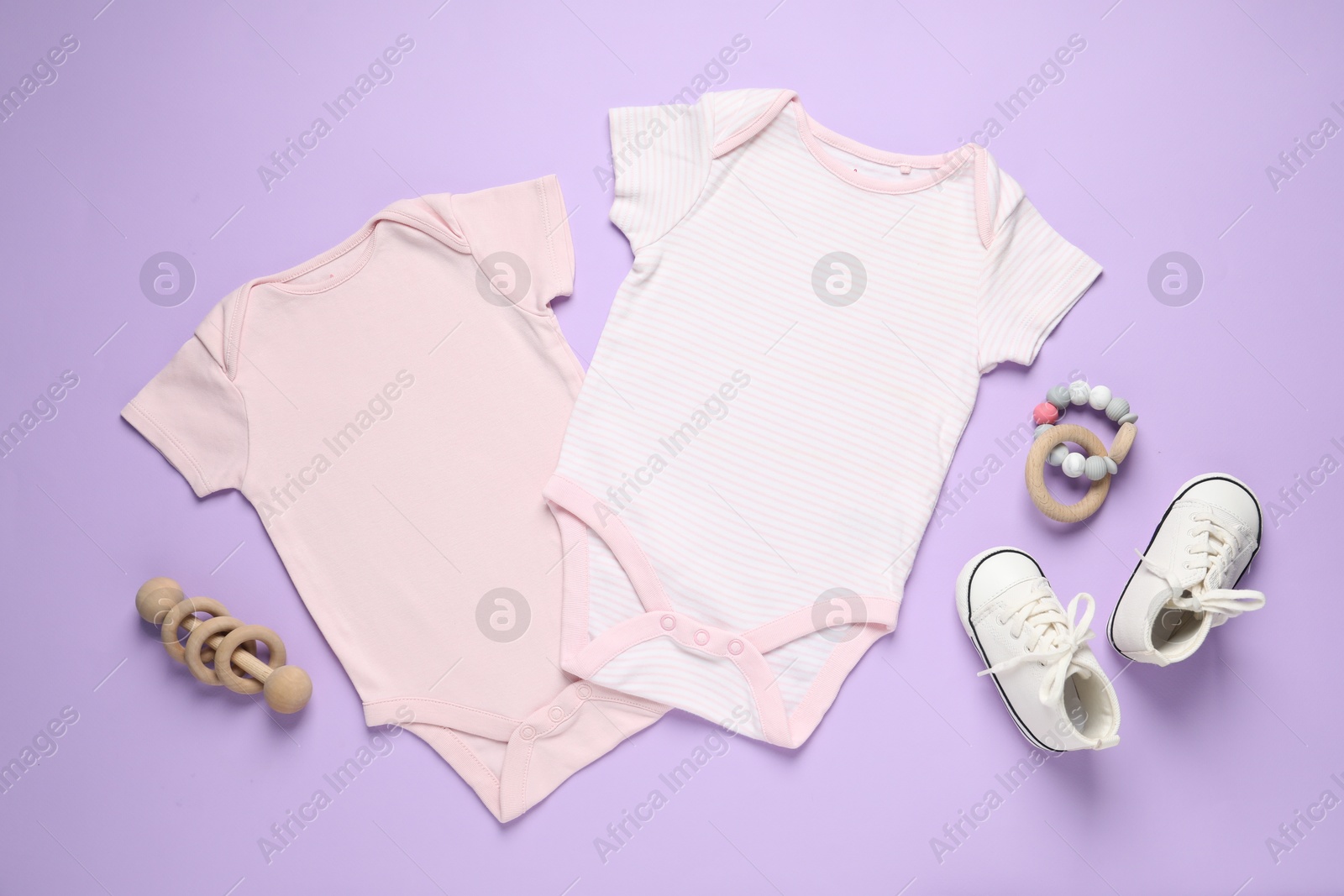 Stylish baby onesies and accessories on violet background, flat lay Photo of Stylish baby onesies and accessories on violet background, flat lay