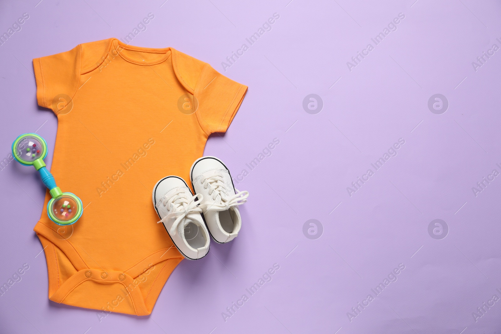 Stylish baby clothes and accessory on violet background, flat lay. Space for text Photo of Stylish baby clothes and accessory on violet background, flat lay. Space for text