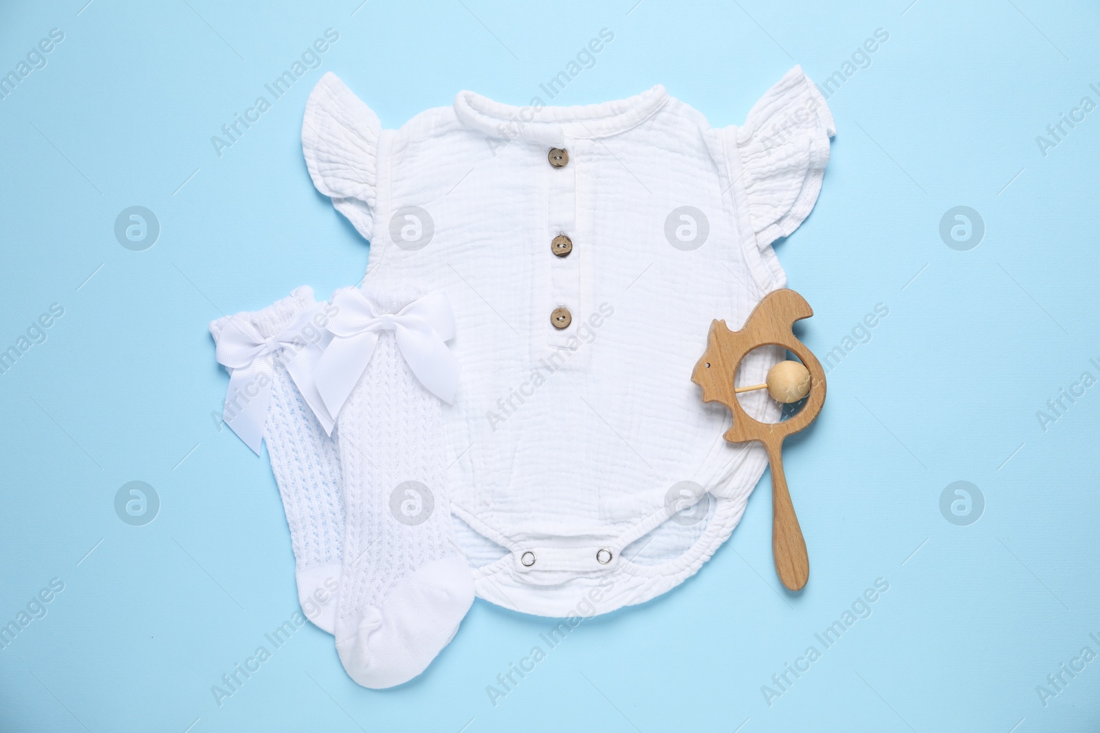 Stylish baby onesie and accessories on light blue background, flat lay Photo of Stylish baby onesie and accessories on light blue background, flat lay