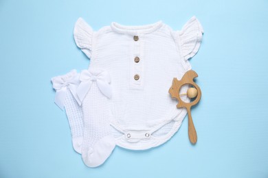 Photo of Stylish baby onesie and accessories on light blue background, flat lay
