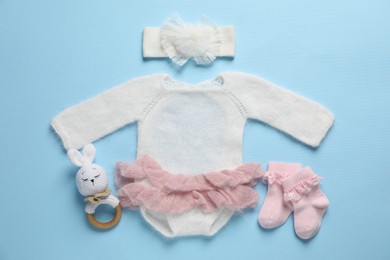 Photo of Stylish baby clothes and accessories on light blue background, flat lay