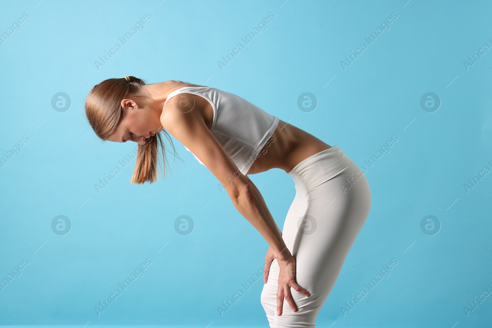 Woman doing abdominal vacuum exercise on light blue background Photo of Woman doing abdominal vacuum exercise on light blue background