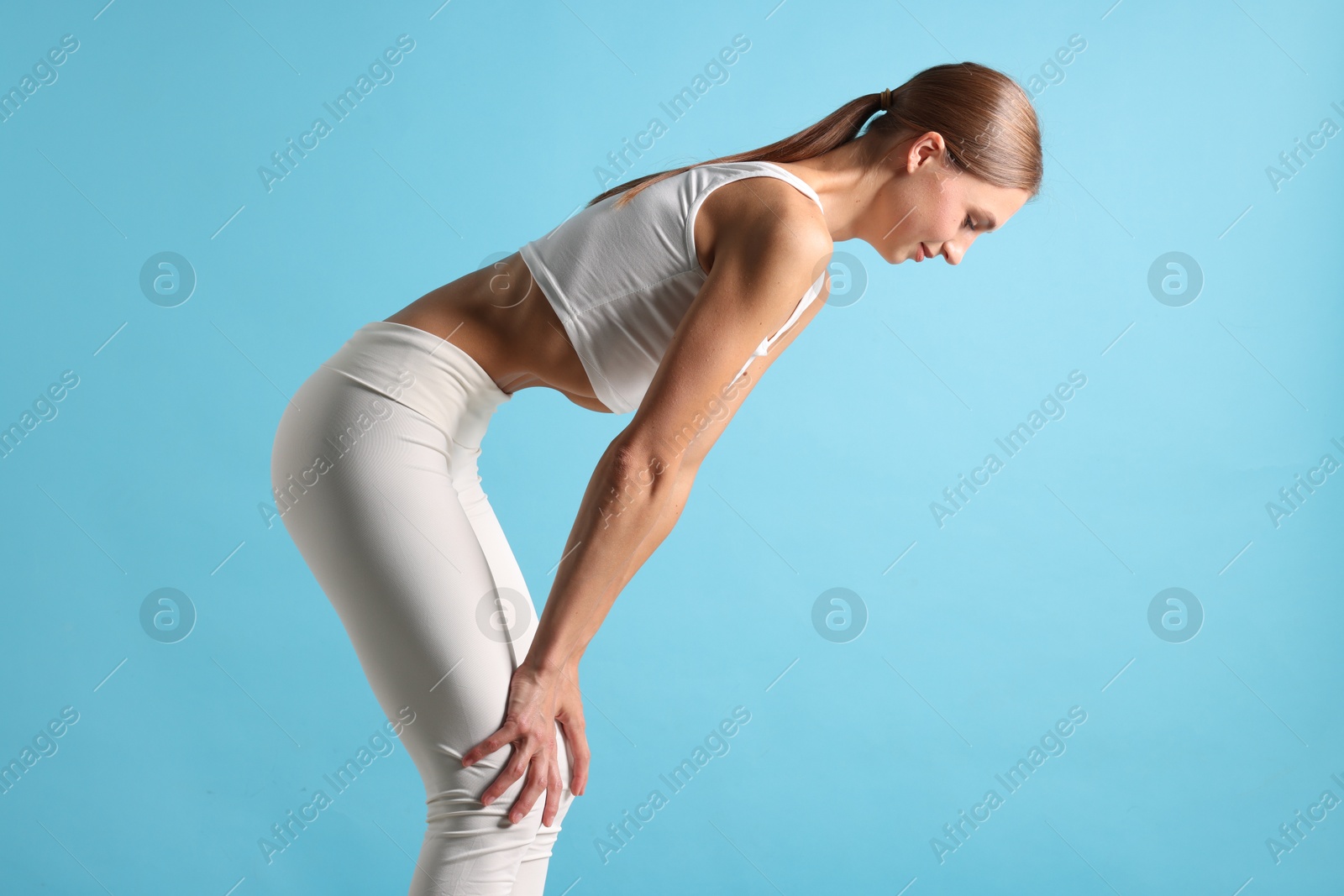 Woman doing abdominal vacuum exercise on light blue background Photo of Woman doing abdominal vacuum exercise on light blue background