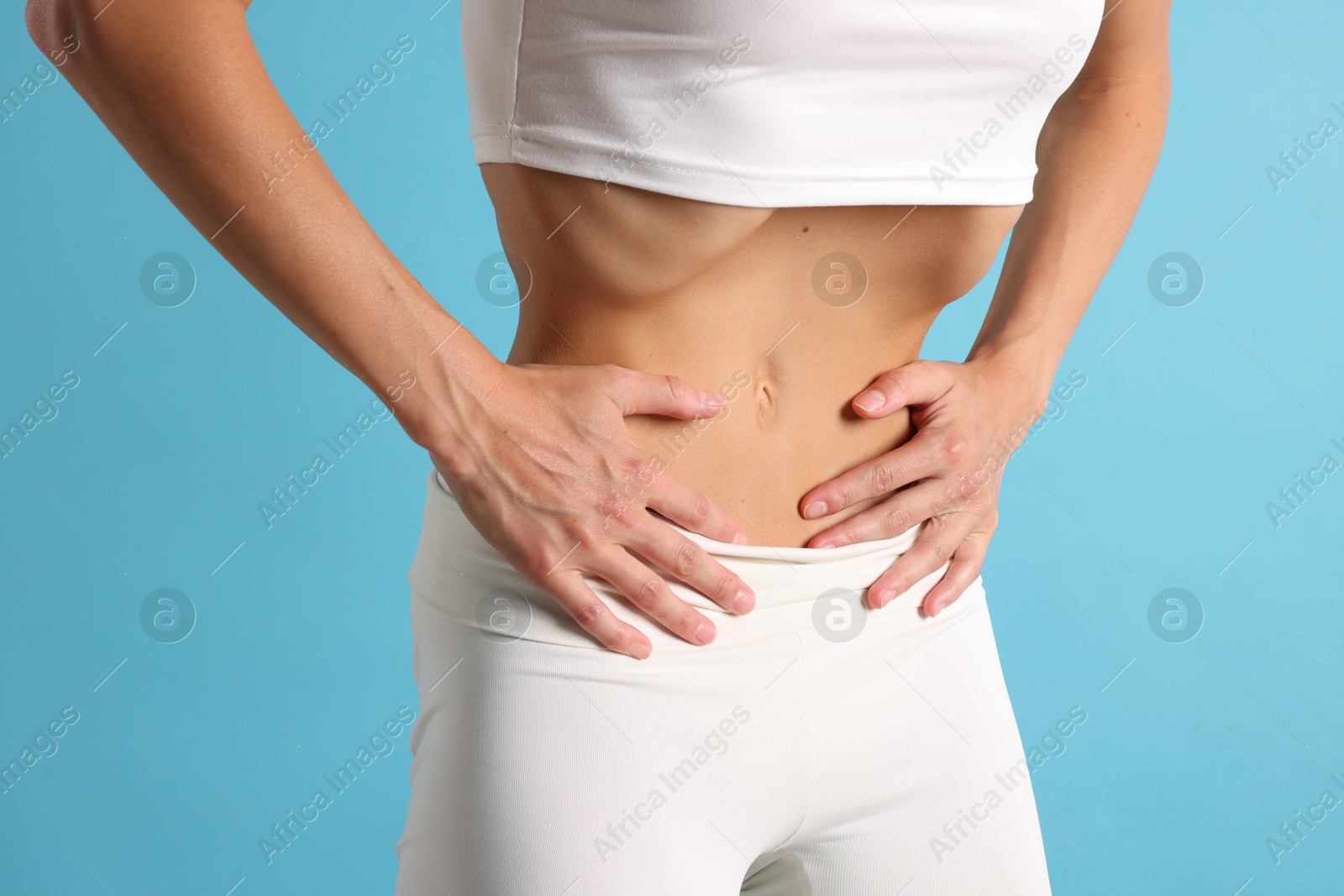 Woman doing abdominal vacuum exercise on light blue background, closeup Photo of Woman doing abdominal vacuum exercise on light blue background, closeup