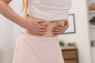 Photo of Woman doing abdominal vacuum exercise at home, closeup