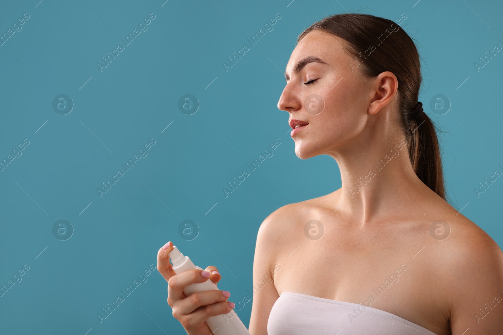 Beautiful woman spraying thermal water on light blue background. Space for text Photo of Beautiful woman spraying thermal water on light blue background. Space for text