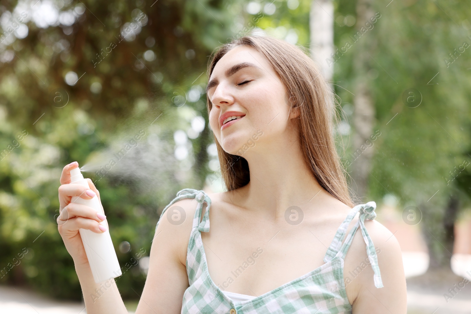 Smiling woman spraying thermal water onto her face outdoors Photo of Smiling woman spraying thermal water onto her face outdoors