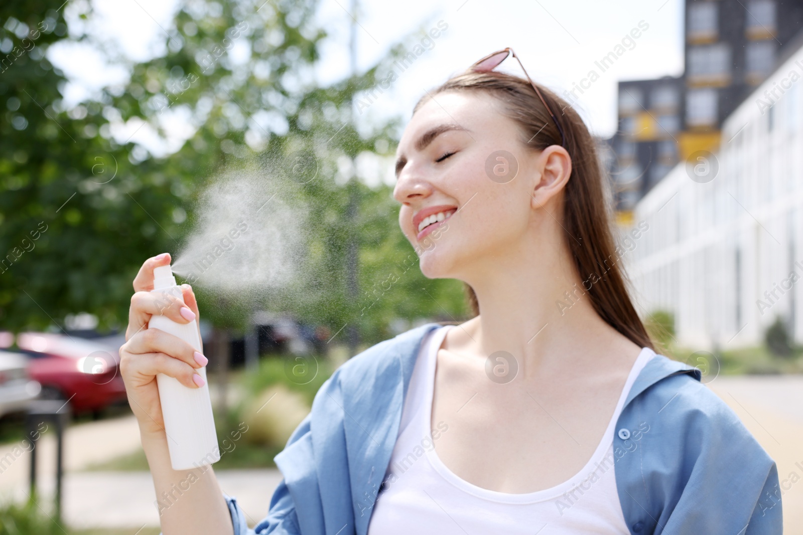 Smiling woman spraying thermal water onto her face outdoors Photo of Smiling woman spraying thermal water onto her face outdoors