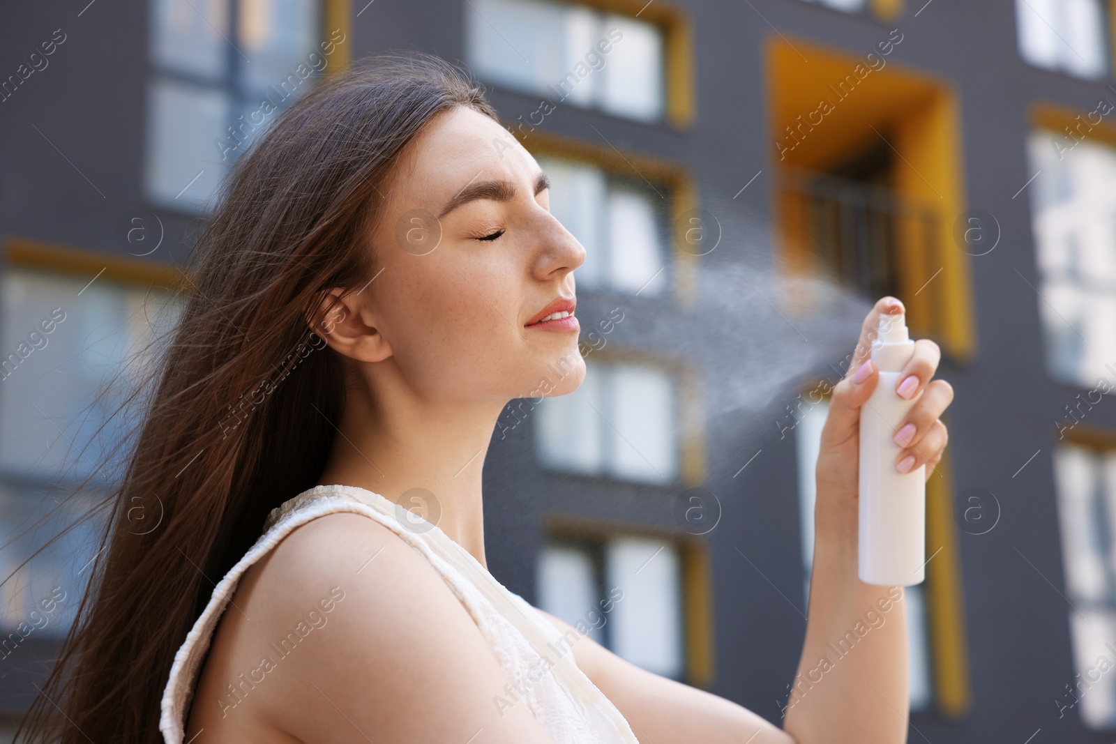 Beautiful woman spraying thermal water onto her face outdoors Photo of Beautiful woman spraying thermal water onto her face outdoors