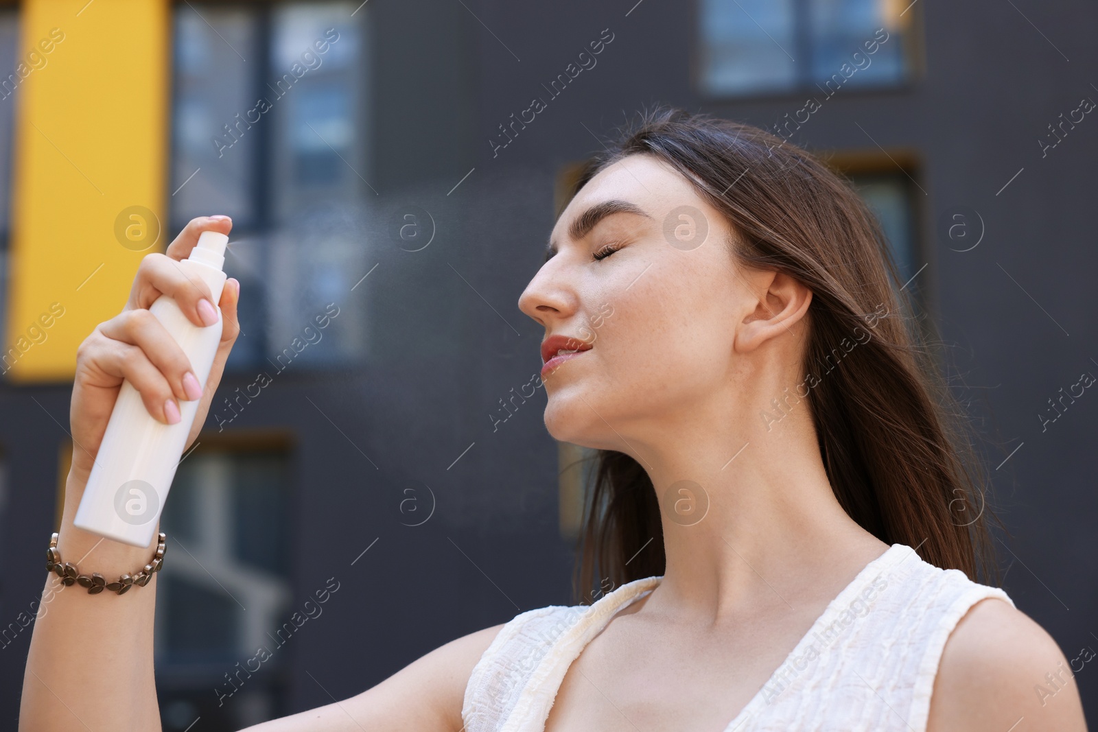 Beautiful woman spraying thermal water onto her face outdoors Photo of Beautiful woman spraying thermal water onto her face outdoors