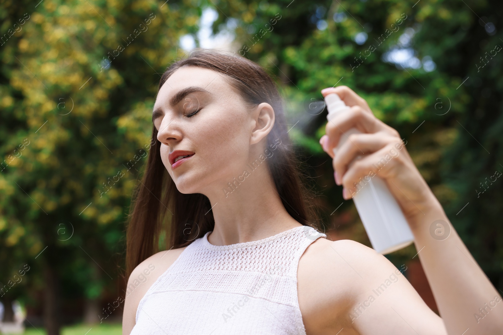 Beautiful woman spraying thermal water onto her face outdoors Photo of Beautiful woman spraying thermal water onto her face outdoors