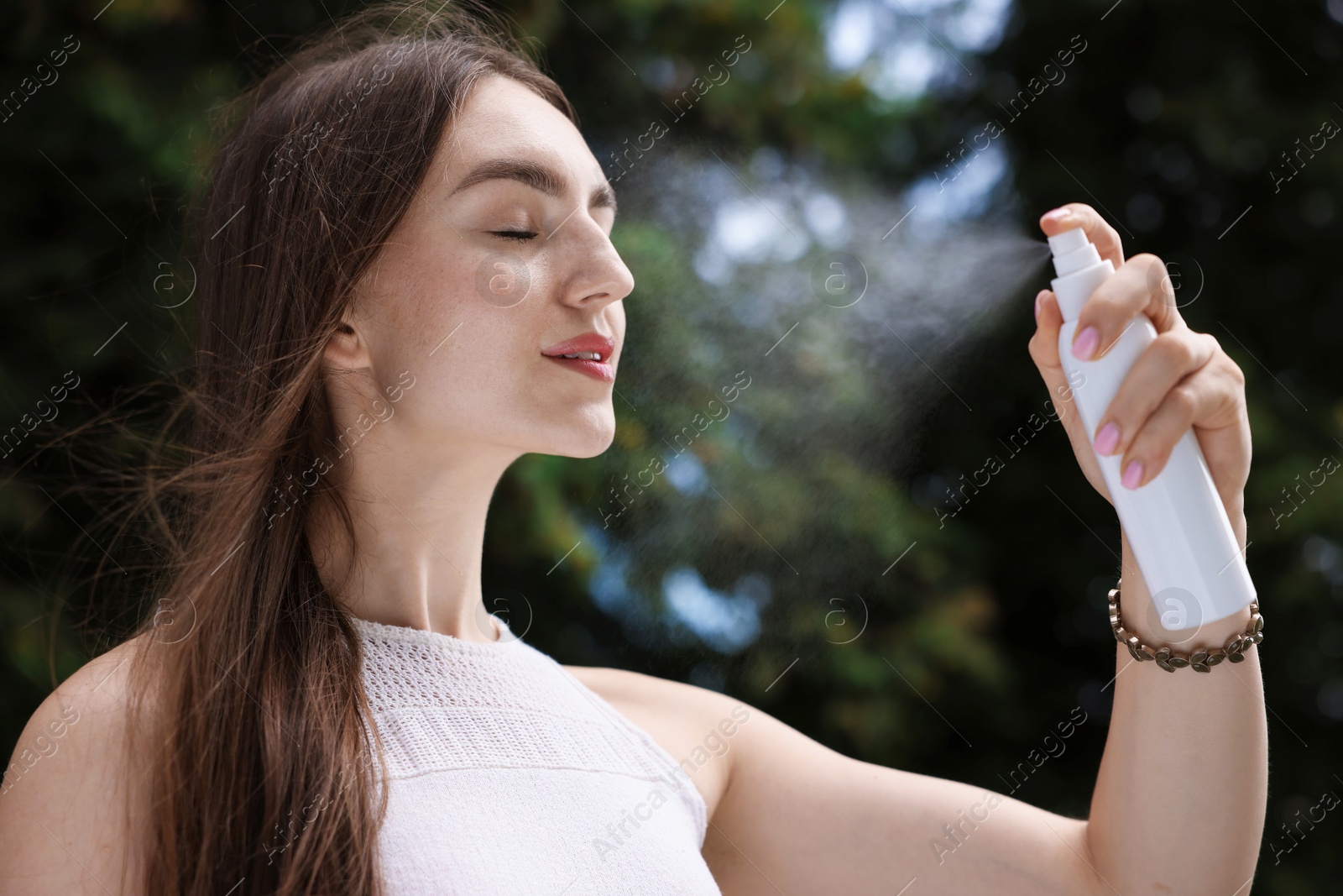 Smiling woman spraying thermal water onto her face outdoors Photo of Smiling woman spraying thermal water onto her face outdoors