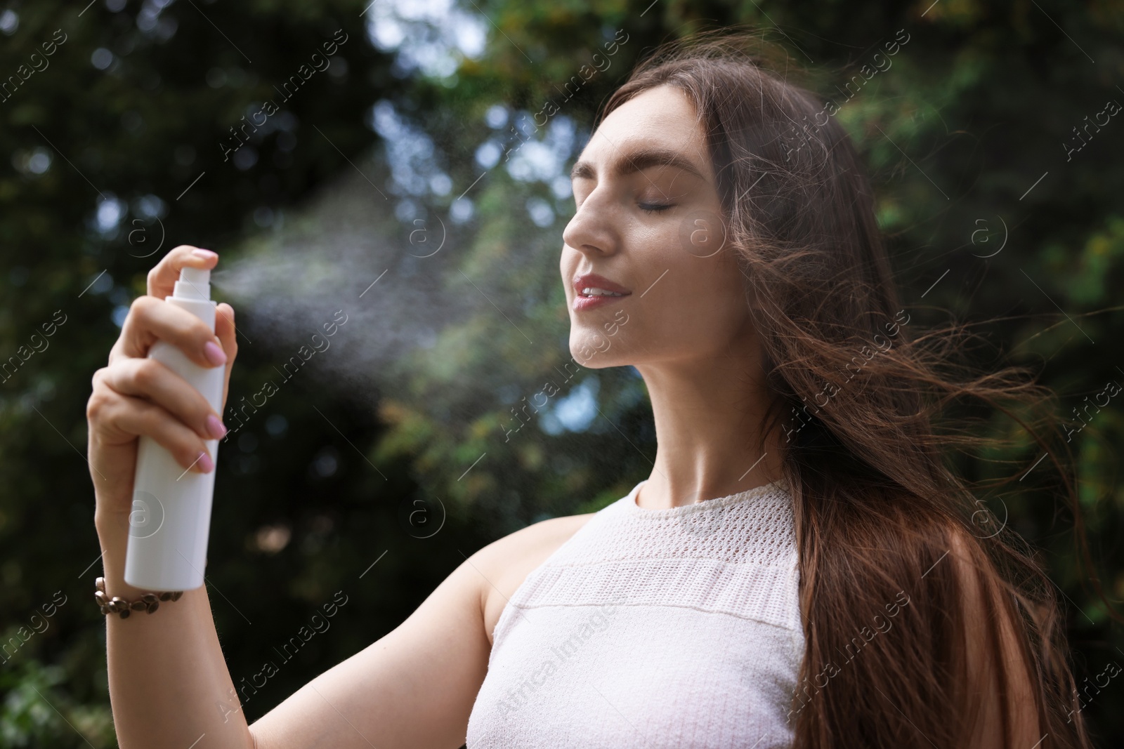 Smiling woman spraying thermal water onto her face outdoors Photo of Smiling woman spraying thermal water onto her face outdoors