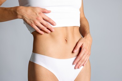 Photo of Woman with flat belly on grey background, closeup