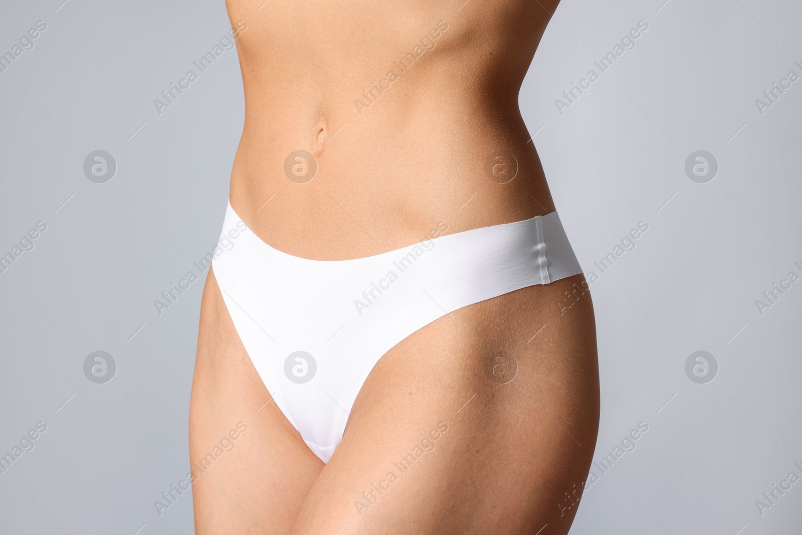 Woman with flat belly on grey background, closeup Photo of Woman with flat belly on grey background, closeup