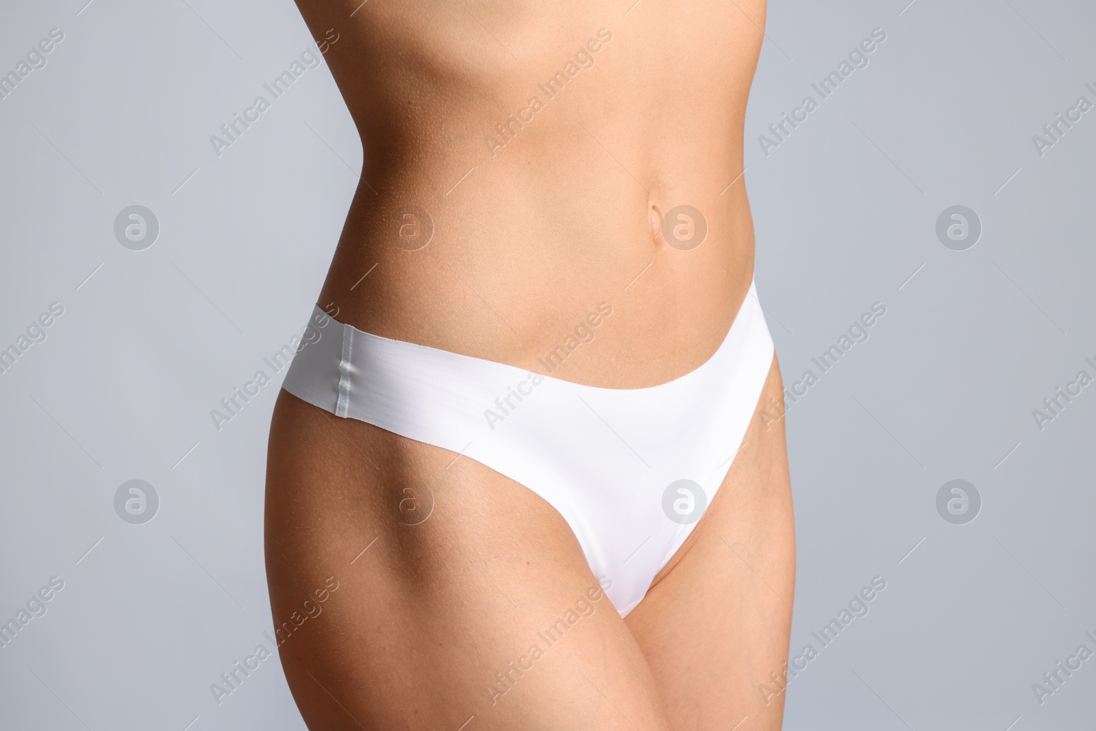Woman with flat belly on grey background, closeup Photo of Woman with flat belly on grey background, closeup
