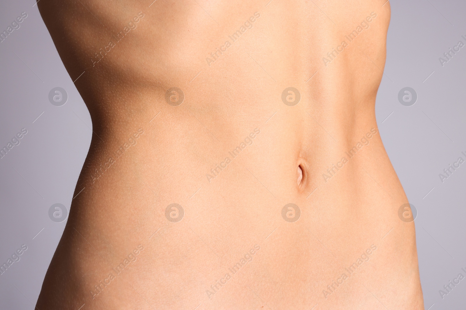 Woman with flat belly on grey background, closeup Photo of Woman with flat belly on grey background, closeup