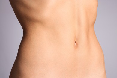 Photo of Woman with flat belly on grey background, closeup