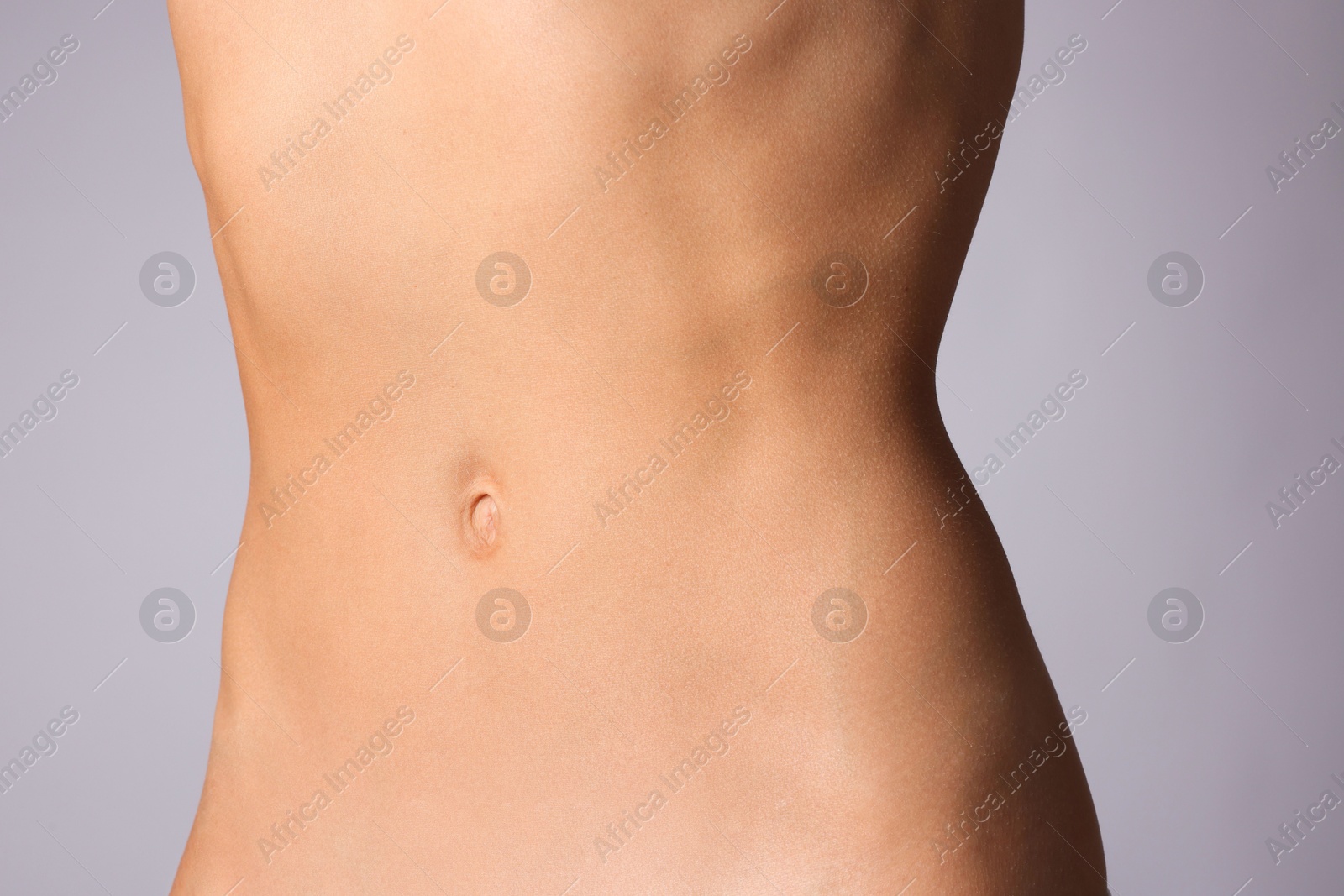 Woman with flat belly on grey background, closeup Photo of Woman with flat belly on grey background, closeup