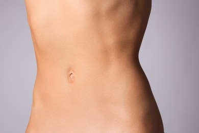 Photo of Woman with flat belly on grey background, closeup