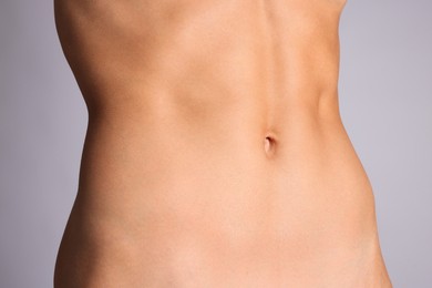 Photo of Woman with flat belly on grey background, closeup